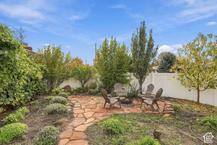 Backyard featuring a flagstone patio, white vinyl privacy fencing, mature trees, and landscaped shrubbery