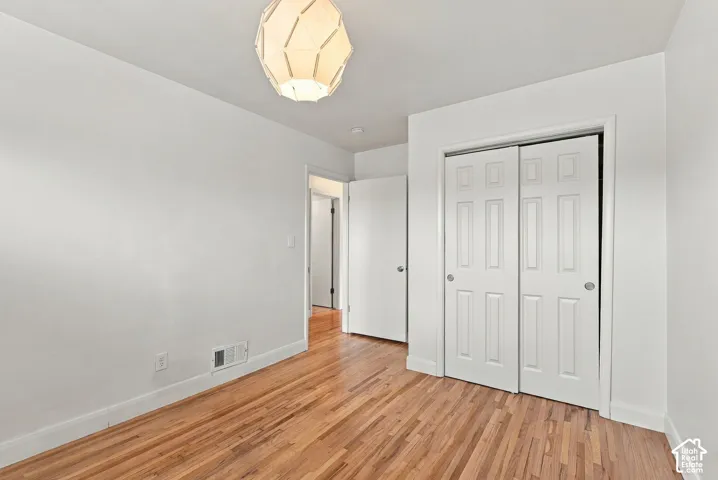 Interior space featuring wood-finish flooring, a geometric pendant light fixture, and a closet with six-panel sliding doors