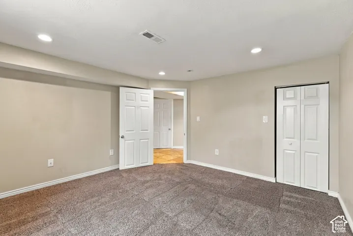 Neutral wall tones, wall-to-wall carpeting, recessed lighting, and white six-panel doors with bi-fold closet doors