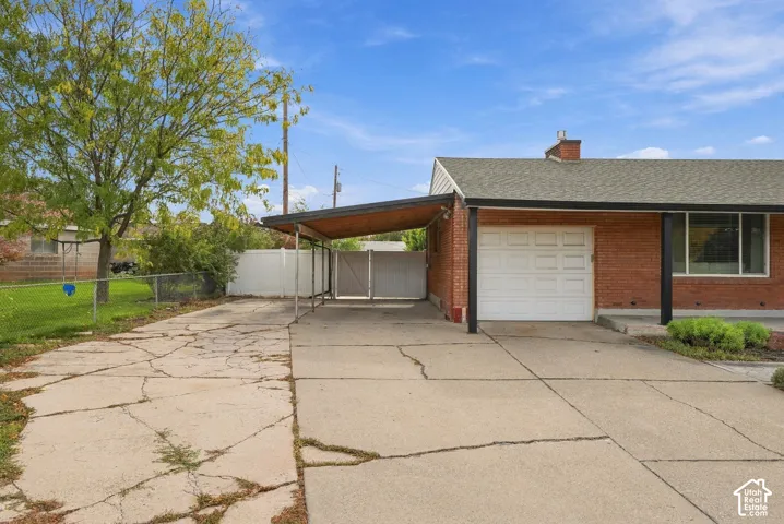 Brick exterior featuring a single-car garage, covered carport, and enclosed side yard