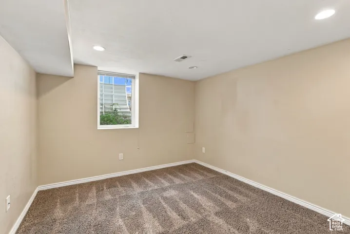Room featuring neutral-toned carpeting, recessed ceiling lighting, and a single-pane window with a metal window well