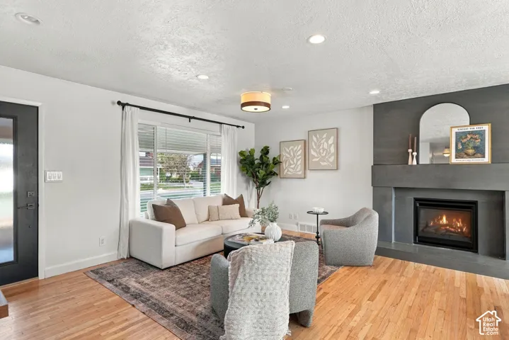 Living area featuring wood-finish flooring, recessed lighting, and a floor-to-ceiling fireplace surround with a built-in hearth
