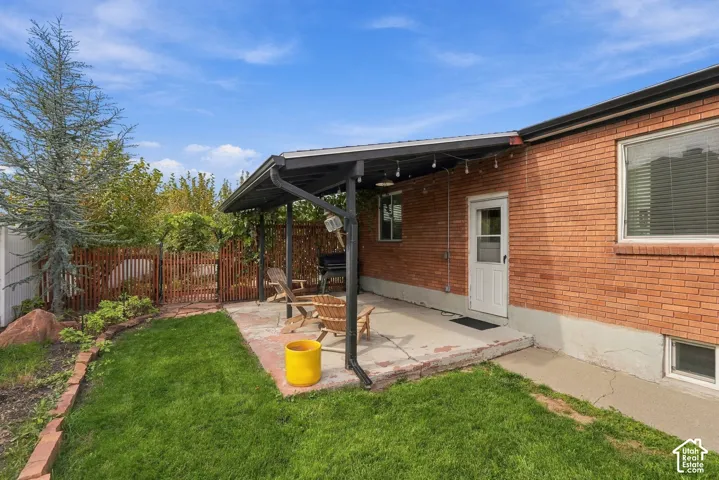 Brick exterior featuring a concrete patio, a covered metal-framed pergola, and an enclosed backyard with a wood-lathe fence