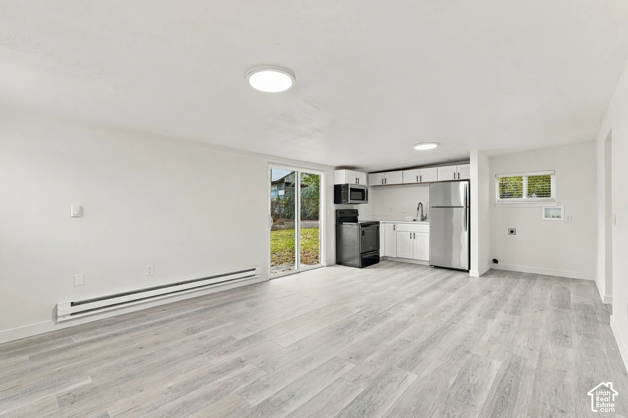 Kitchen featuring white cabinetry, stainless steel appliances, wood-finish flooring, and glass sliding doors