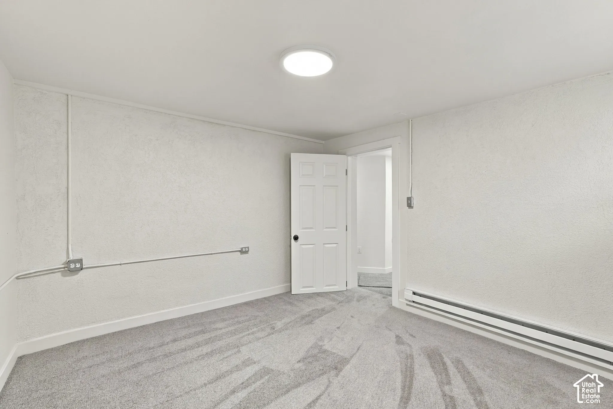Interior space featuring wall-to-wall carpeting, textured wall finish, six-panel door, and flush-mount ceiling lighting