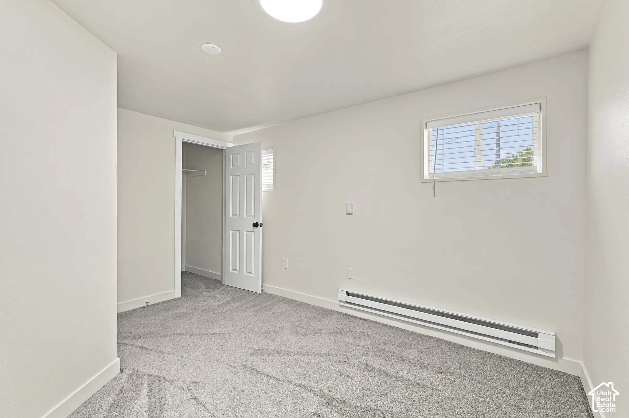 Neutral-toned interior space featuring wall-to-wall carpeting, a six-panel interior door, and a horizontal sliding window