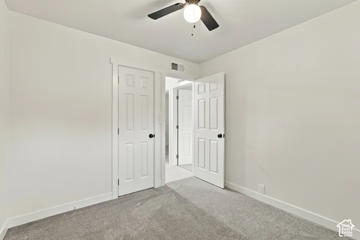 Neutral-toned carpeting, white six-panel interior doors, and a ceiling-mounted light fixture with a fan