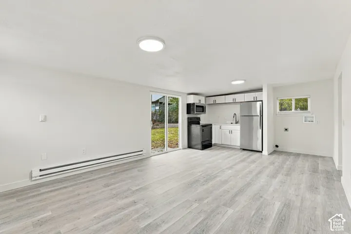 Kitchen featuring white cabinetry, stainless steel appliances, wood-finish flooring, and glass sliding doors