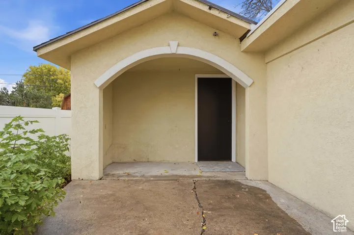 Covered entryway featuring a stucco exterior, an arched architectural detail, and a concrete porch