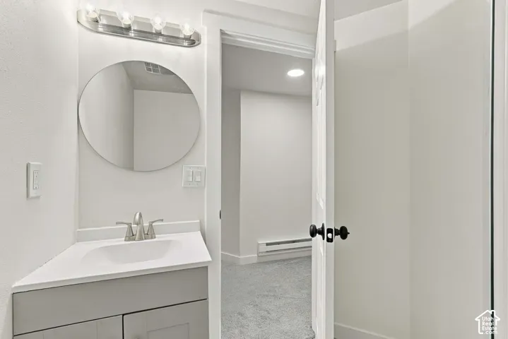 Bathroom featuring a vanity with a white countertop and integrated sink, a circular mirror, and a multi-bulb light fixture