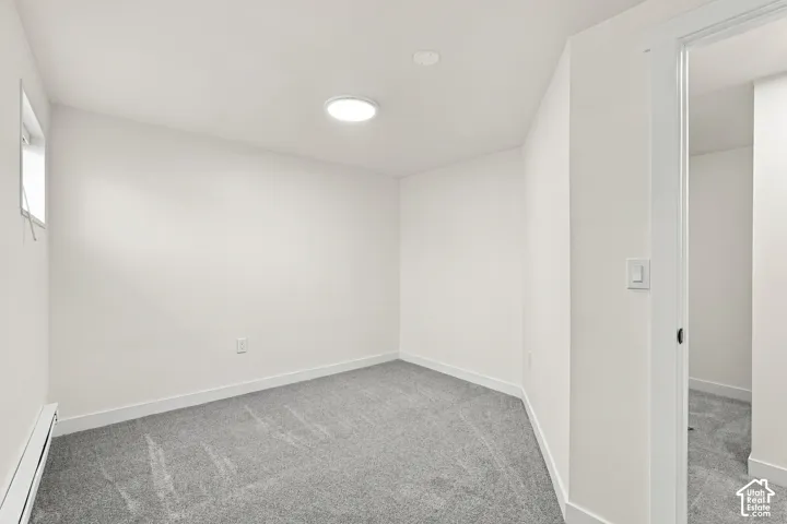 Neutral-toned wall-to-wall carpeting, crisp white walls, flush-mount overhead lighting, and an entryway featuring a white-cased door