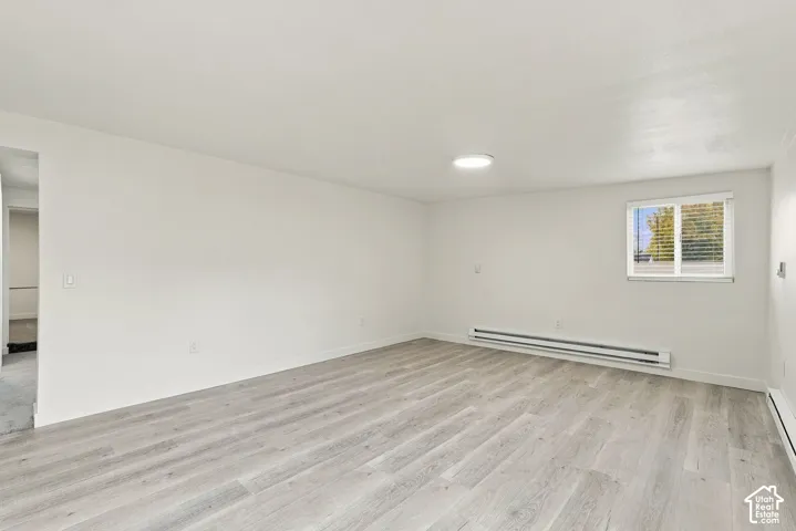Interior space featuring neutral wall paint, wood-finish flooring, a flush-mount ceiling light, and a double-pane window