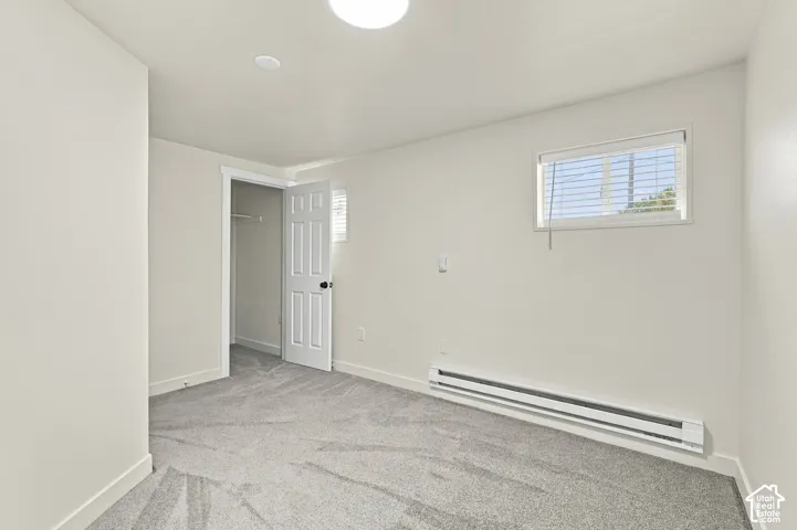 Neutral-toned interior space featuring wall-to-wall carpeting, a six-panel interior door, and a horizontal sliding window