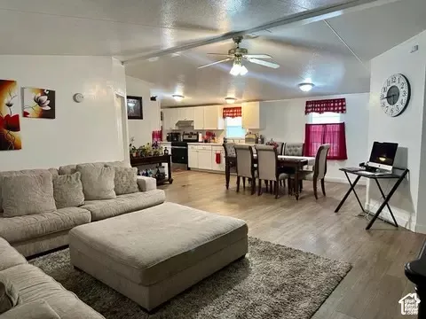 Open-concept floor plan featuring wood-finish flooring, recessed lighting, ceiling fan, and white cabinetry