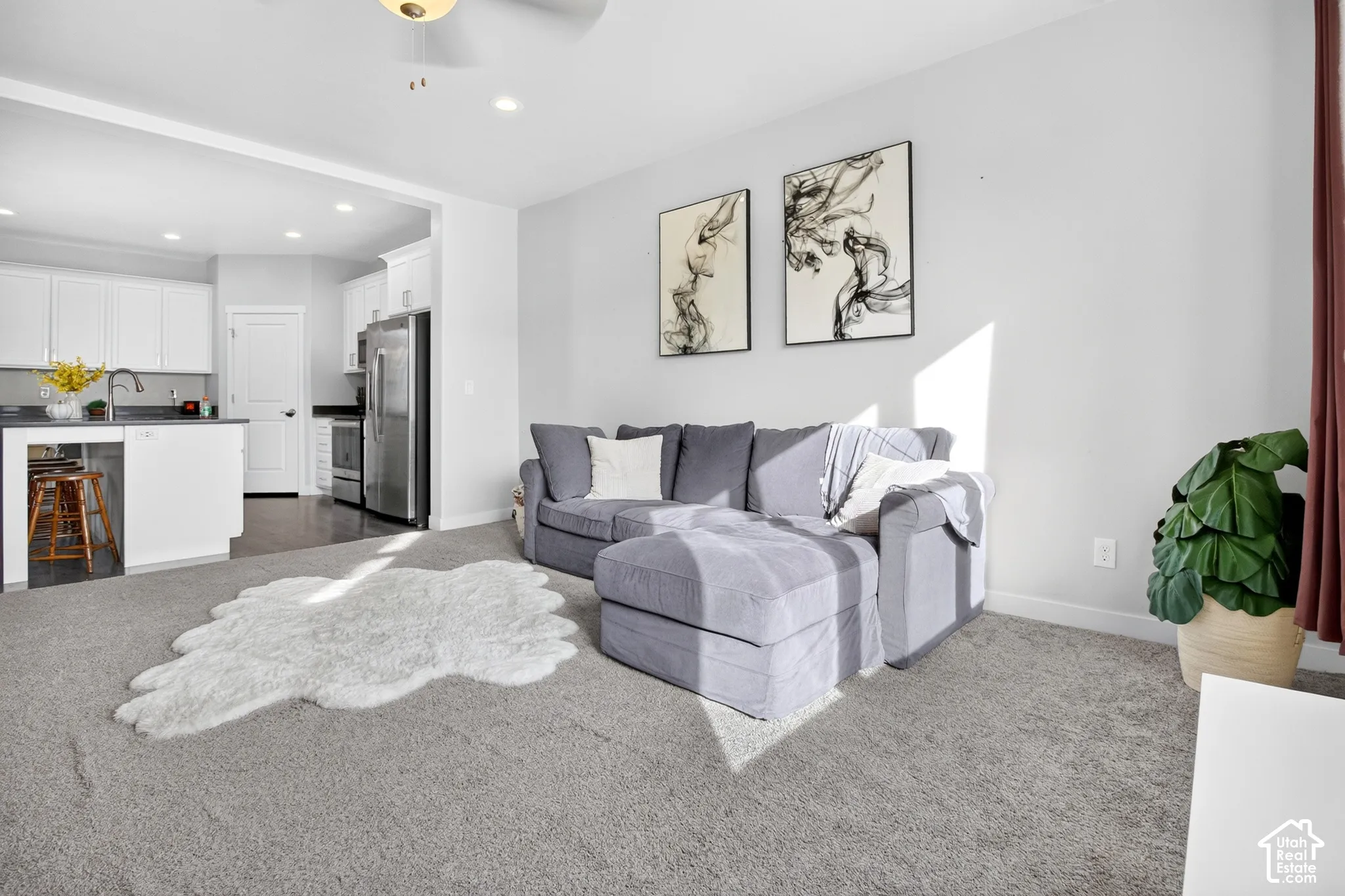 Neutral-toned wall-to-wall carpeting, recessed ceiling lighting, and a white kitchen island featuring a countertop surface