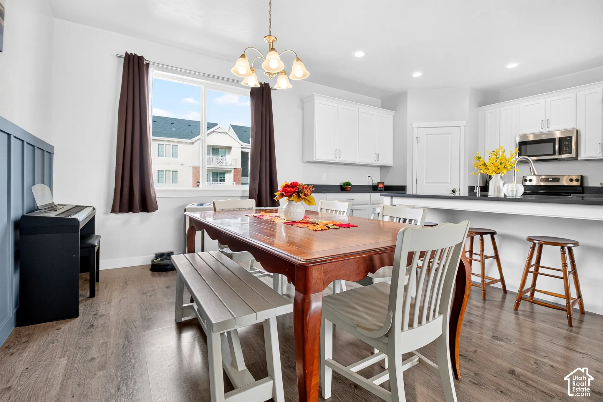 Kitchen featuring white cabinetry, dark countertops, built-in stainless steel appliances, wood-finish flooring, and a decorative board-and-batten accent wall