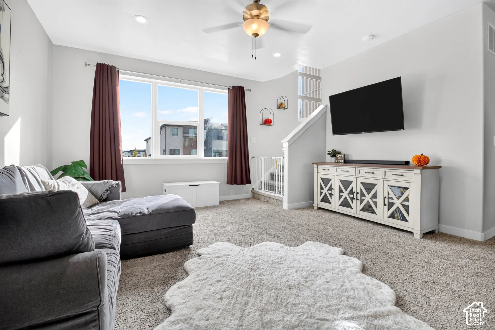 Living area featuring neutral wall tones, plush wall-to-wall carpeting, recessed lighting, and a ceiling fan with integrated light fixture