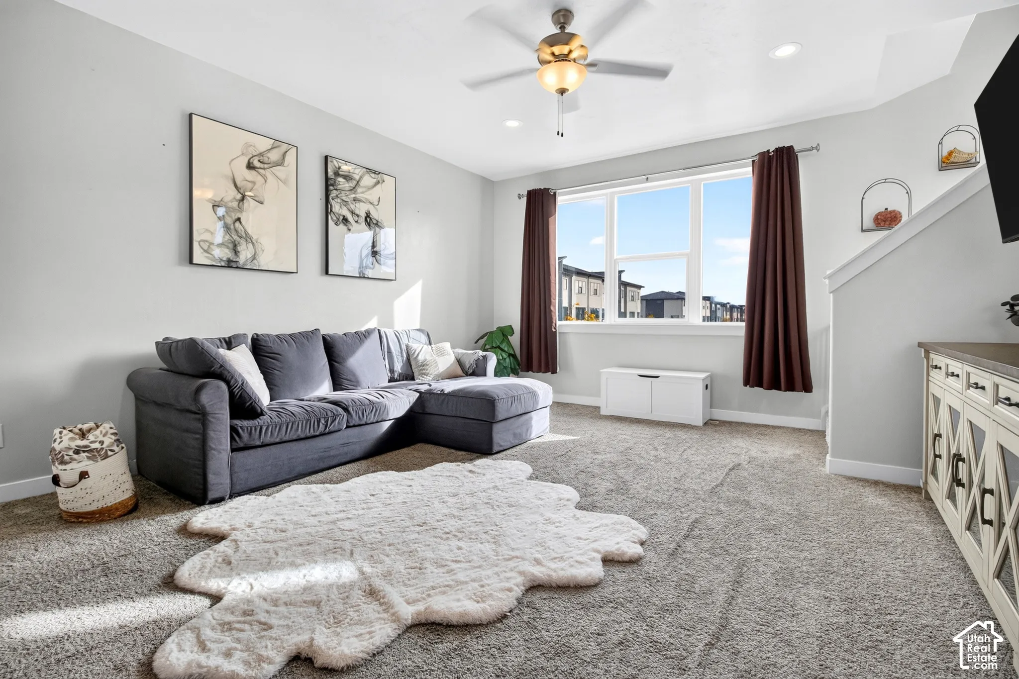 Neutral-toned interior featuring wall-to-wall carpeting, recessed ceiling lighting, a multi-blade ceiling fan with integrated light fixture, and a large multi-pane window