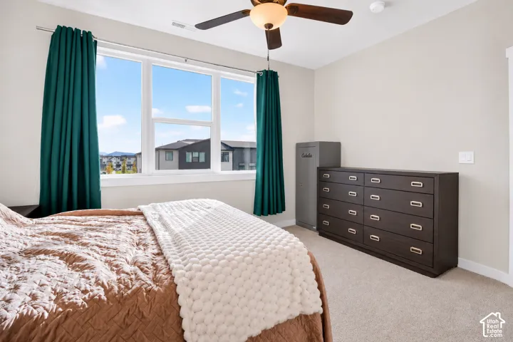 Large window featuring neutral wall tones, carpeted flooring, and a ceiling fan with integrated light fixture