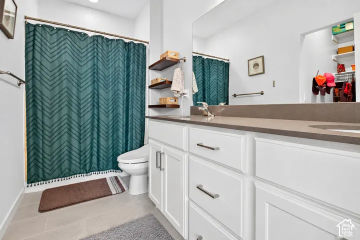 Bathroom featuring white cabinetry, solid-surface countertop with integrated sink, large wall-mounted mirror, built-in wall shelving, and tub-shower combination