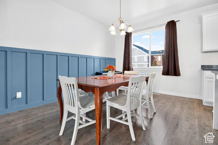 Blue wainscoting featuring board and batten detailing, wood-finish flooring, multi-light chandelier, and large sliding window