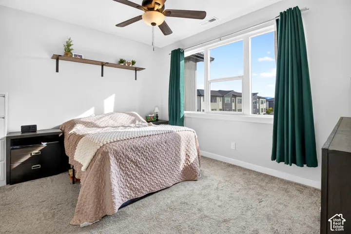 Room featuring neutral carpeting, a large multi-pane window, and a ceiling fan with integrated lighting