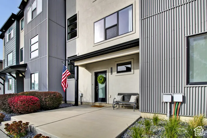 Contemporary exterior featuring stucco siding, corrugated metal accents, large rectangular windows, and a covered concrete entryway