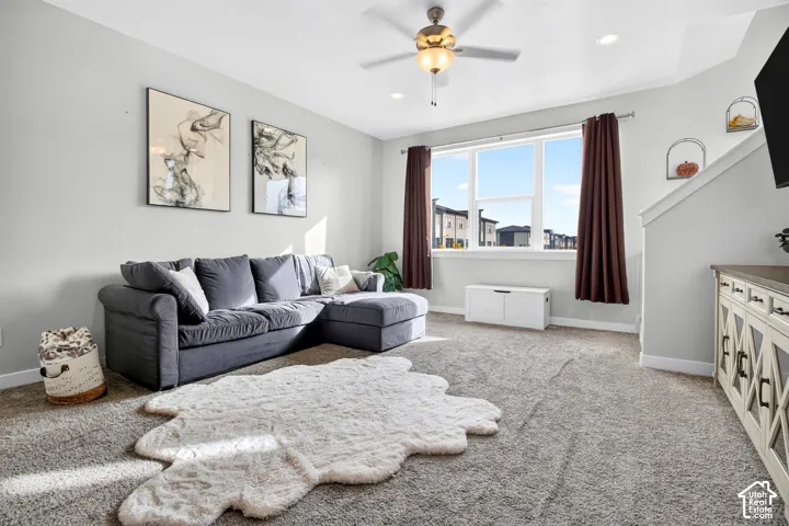 Neutral-toned interior featuring wall-to-wall carpeting, recessed ceiling lighting, a multi-blade ceiling fan with integrated light fixture, and a large multi-pane window
