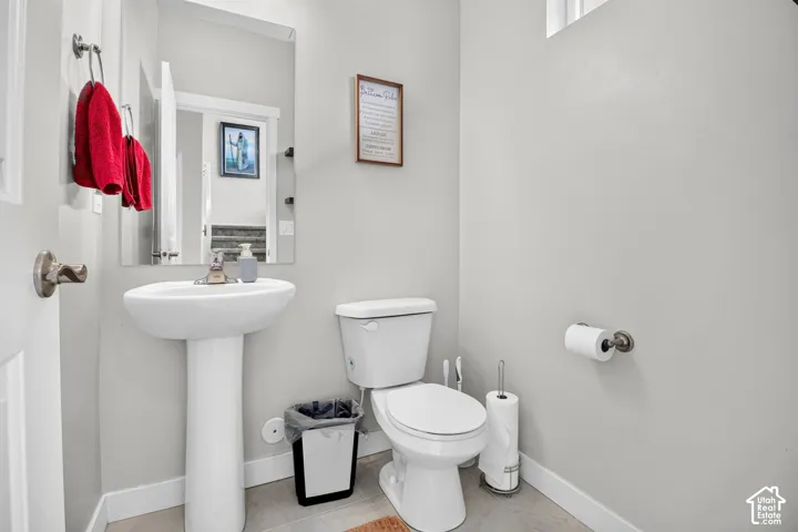 Pedestal sink featuring a polished metal faucet, wall-mounted mirror, neutral interior paint, and tile flooring