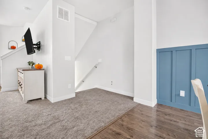 Interior space featuring blue board-and-batten wainscoting, neutral carpeting, and wood-finish flooring