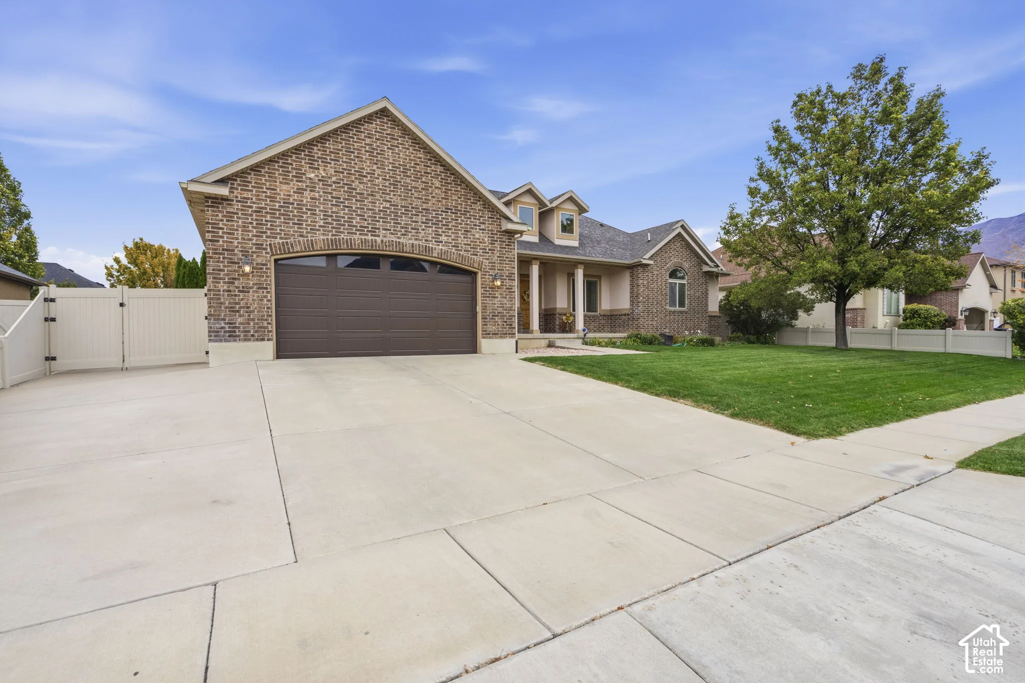 Brick exterior featuring a multi-car garage, arched garage entry, 34 ft concrete side parking, and white perimeter fencing