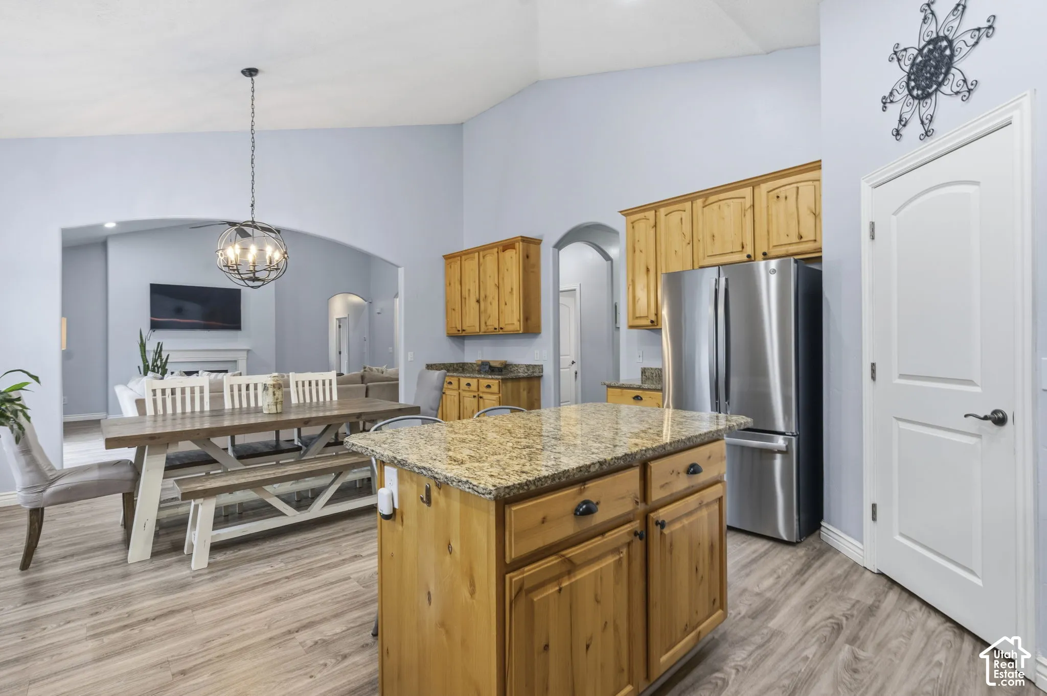 Kitchen featuring a center island, stone countertops, wood cabinetry, vaulted ceilings, and stainless steel refrigerator