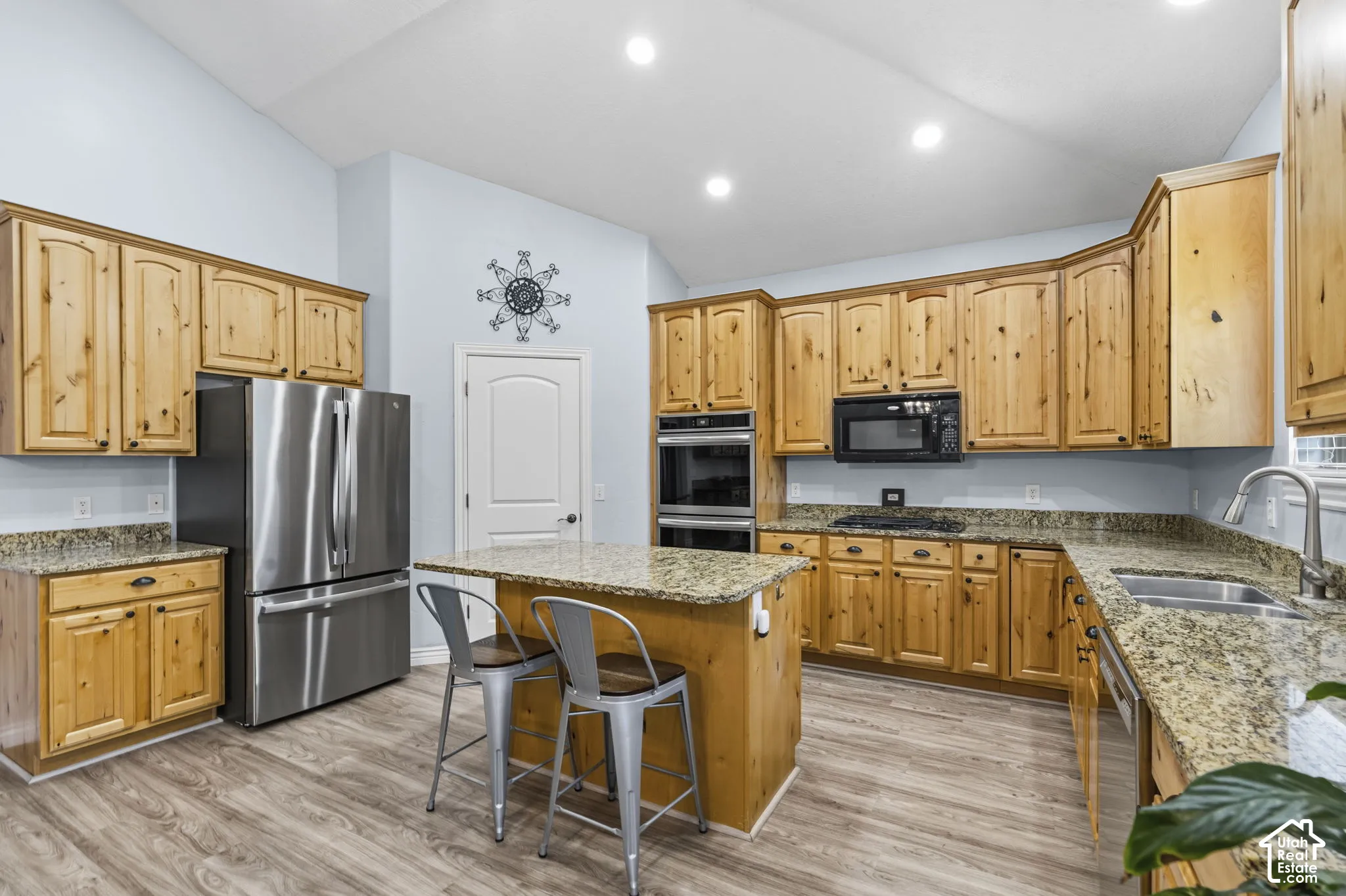 Kitchen featuring natural wood cabinetry, stone-surface countertops, stainless steel double wall ovens, a central island, and recessed lighting