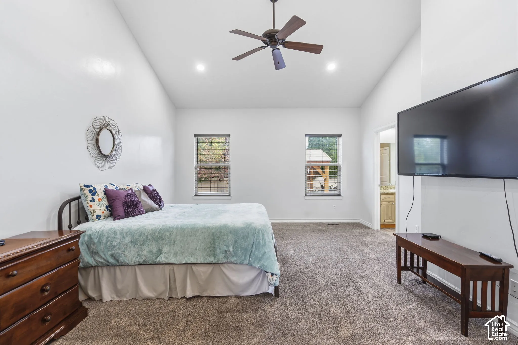 Primary Bedroom with vaulted ceiling featuring a central dark-finish ceiling fan and recessed lighting, accented by neutral-toned carpeting and dual windows with blinds