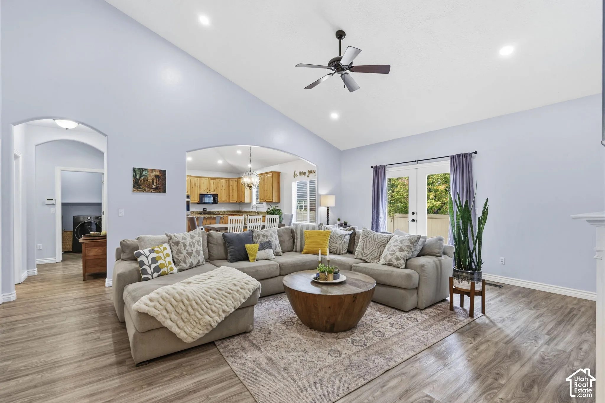 Vaulted ceilings, wood-finish flooring, arched doorways, recessed lighting, and double glass doors