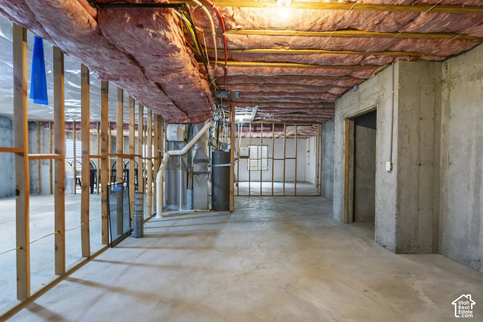 Unfinished lower level featuring concrete flooring, exposed wood framing, concrete foundation walls, and insulation