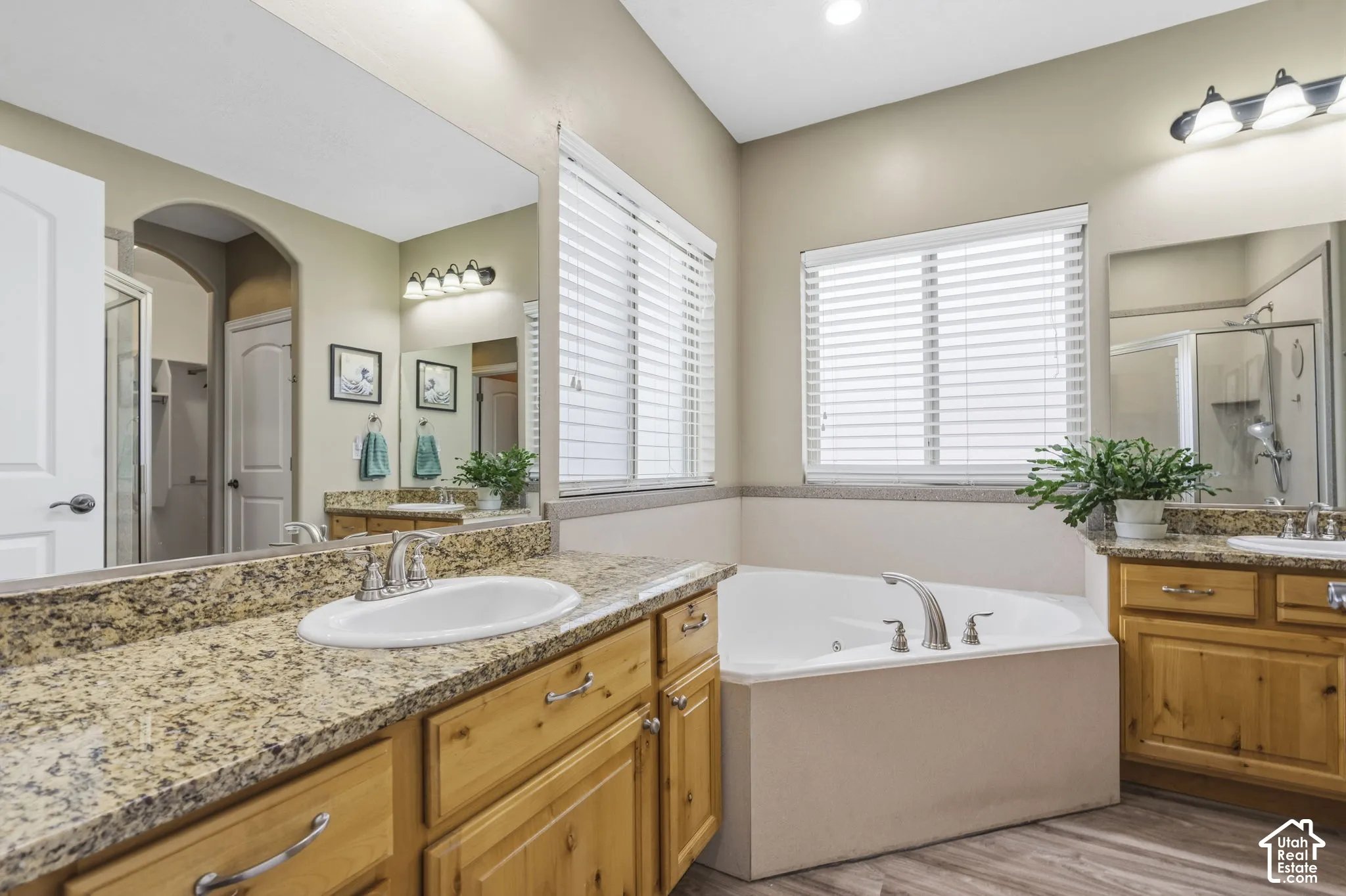 Dual-sink vanity featuring light-finish cabinetry, granite countertops, and large wall-mounted mirrors