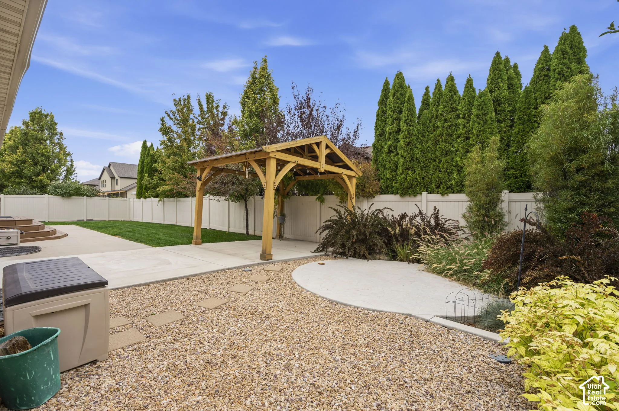 Backyard featuring a wood-frame gazebo, concrete patio, gravel landscaping, and a solid privacy fence