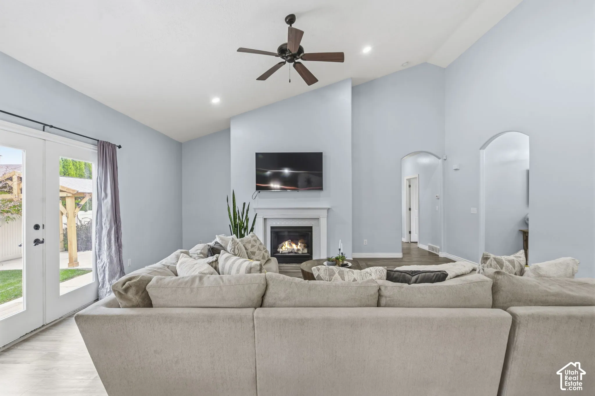 Vaulted ceilings, fireplace with custom mantel, arched doorways, recessed lighting, and glass-paneled double doors