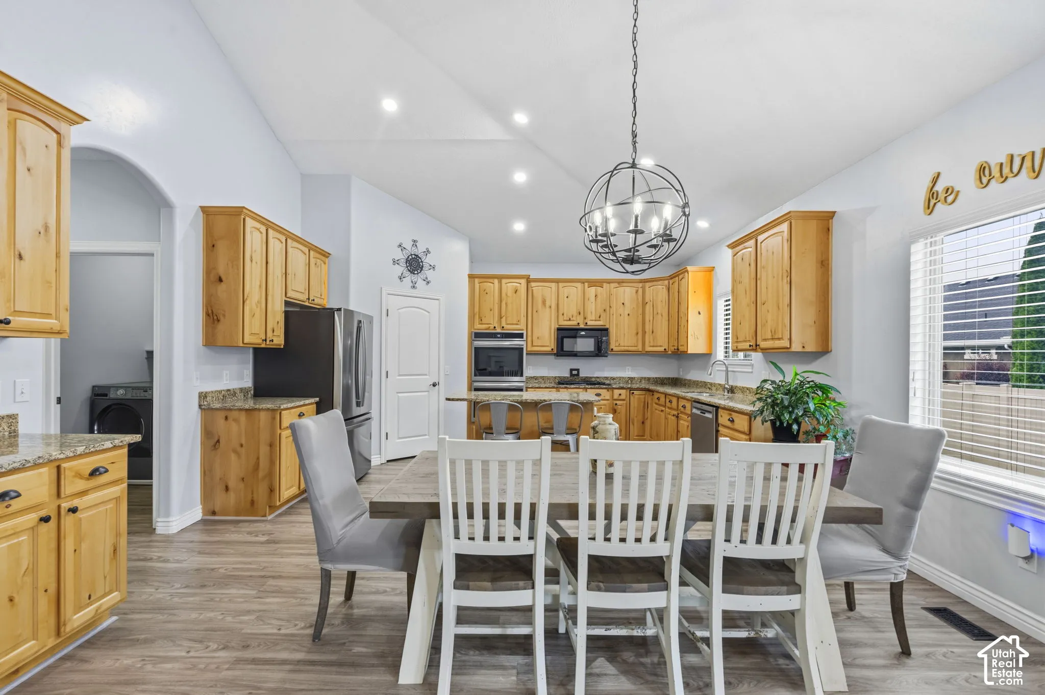 Kitchen featuring wood cabinetry, stone countertops, stainless steel wall-mounted oven and microwave, vaulted ceiling with recessed lighting, and wood-finish flooring