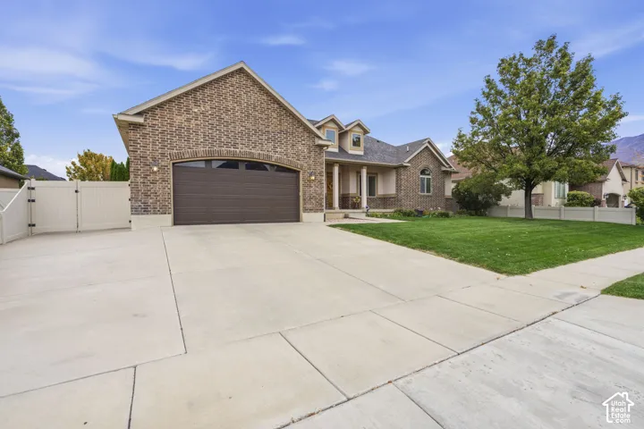Brick exterior featuring a multi-car garage, arched garage entry, 34 ft concrete side parking, and white perimeter fencing