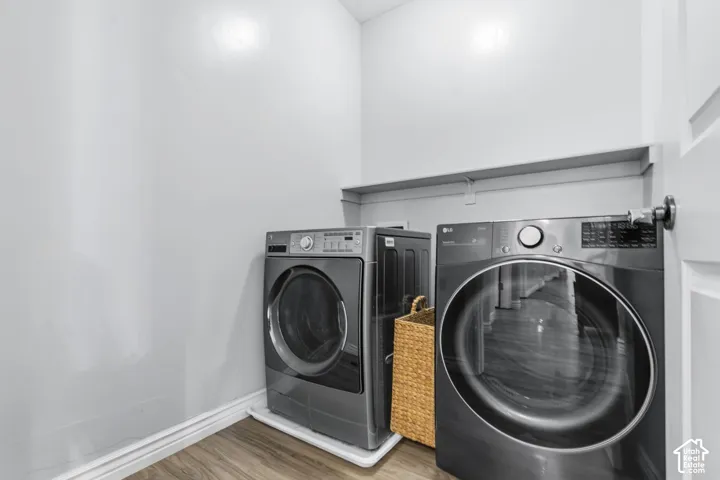 Dedicated laundry space featuring wood-finish flooring and a built-in overhead storage shelf