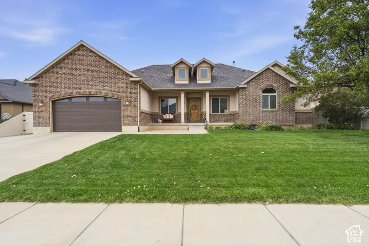Brick exterior featuring a multi-gabled roofline, dual roof dormers, arched entryway, and an attached multi-car garage