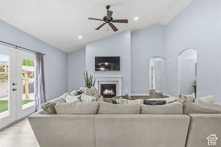 Vaulted ceilings, fireplace with custom mantel, arched doorways, recessed lighting, and glass-paneled double doors