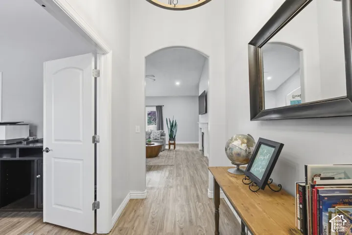 Foyer featuring vaulted ceilings, an arched entryway, wood-finish flooring, and a circular drum pendant light