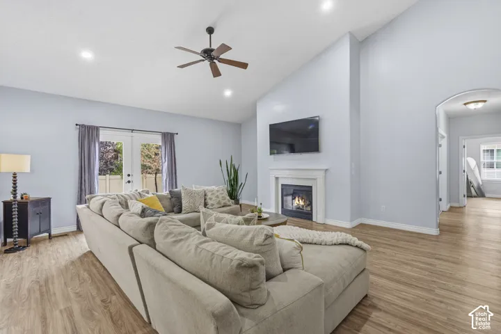 Vaulted ceilings, wood-finish flooring, built-in fireplace with a crisp white mantel, recessed lighting, and glass-paned double doors
