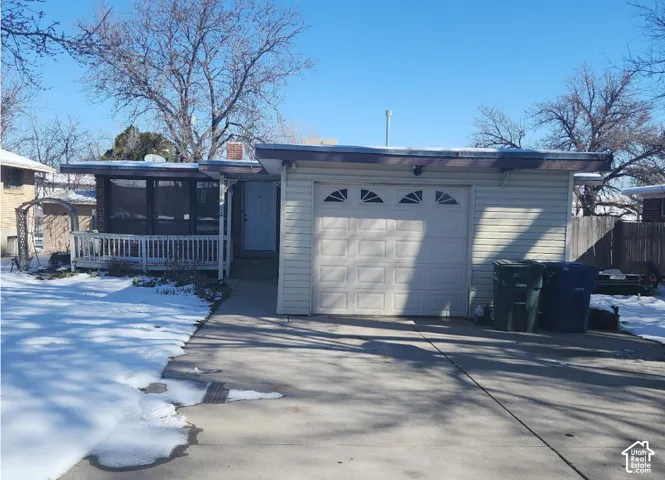 Single-story exterior featuring light-toned horizontal siding, an attached one-car garage with an arched-window sectional door, and a covered porch with white railing