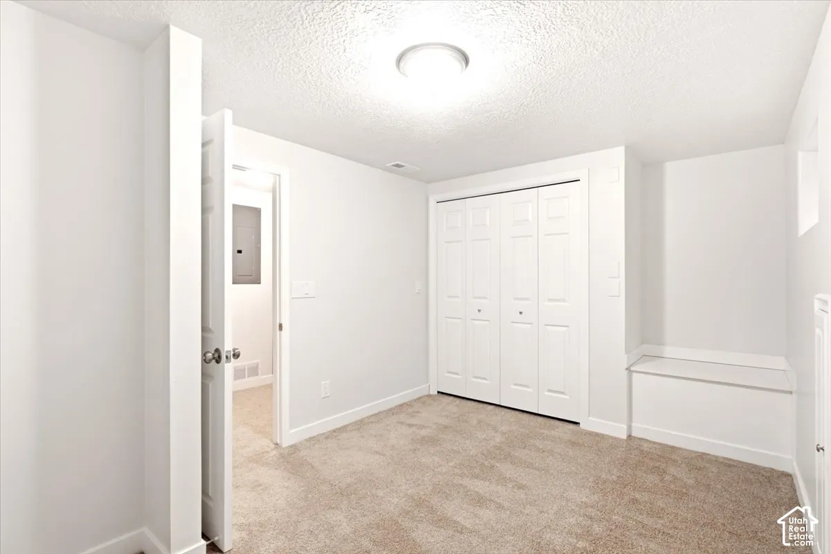 Neutral-toned carpeting, white bi-fold closet doors, built-in window seat, and flush-mount ceiling lighting