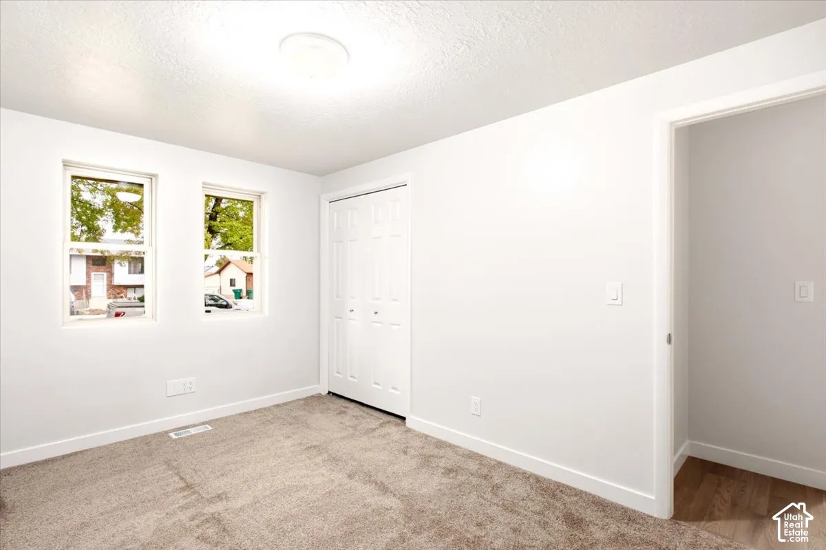 Neutral-toned interior featuring wall-to-wall carpeting, dual-pane windows, and a built-in bifold closet