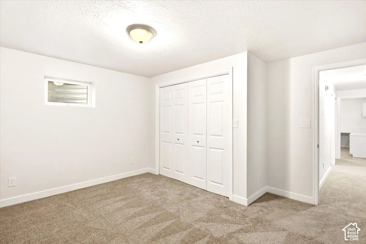 Neutral-toned carpeting, white walls, and a bi-fold closet with panel doors